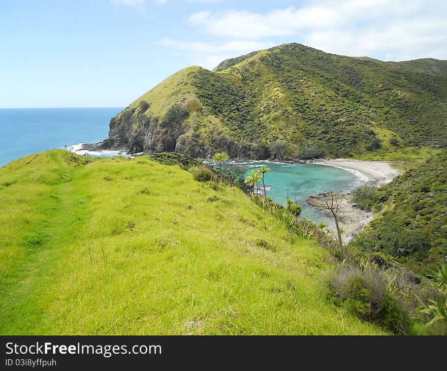 A little beach with pristine water surrounded by green mountains and vegetation. A little beach with pristine water surrounded by green mountains and vegetation