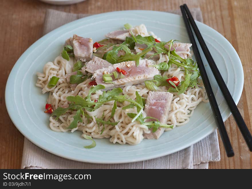 Tuna steak with wasabi noodles and rocket on a plate. Tuna steak with wasabi noodles and rocket on a plate