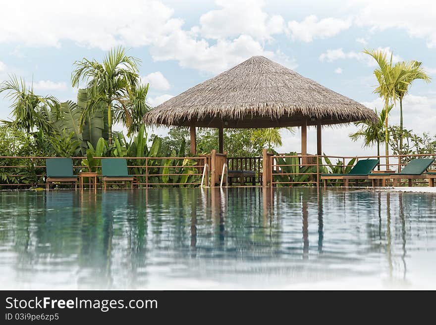 View of nice tropical pool with exotic hut on the back