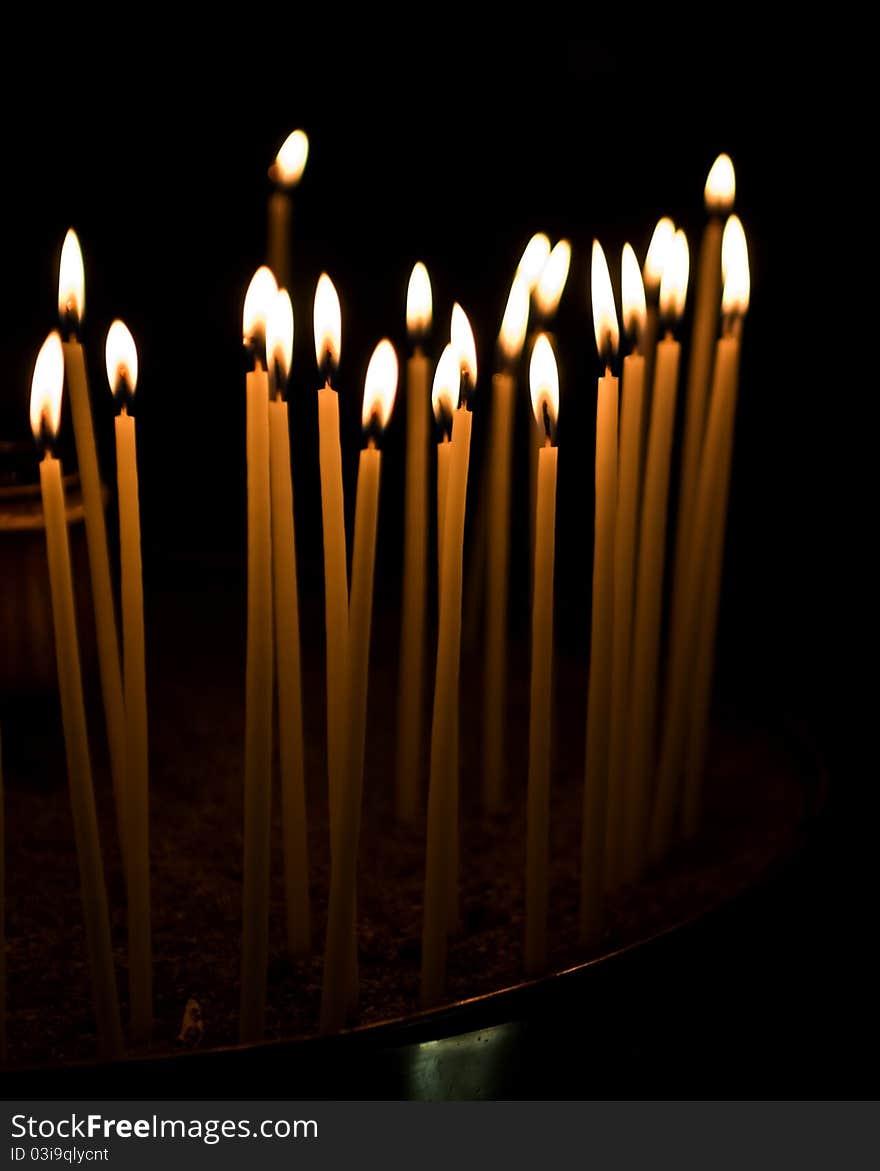 Burning votive candles in a Greek church over dark background. Burning votive candles in a Greek church over dark background.