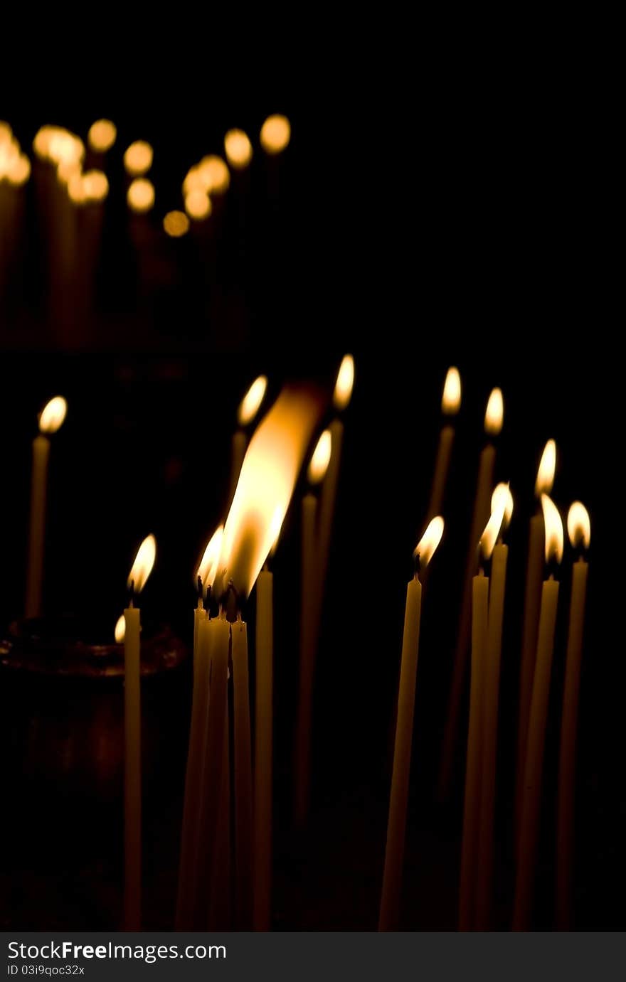 Burning votive candles in a Greek church over dark background. Burning votive candles in a Greek church over dark background.