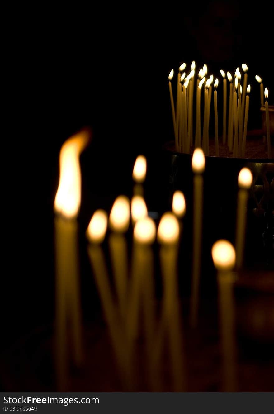 Burning votive candles in a Greek church over dark background. Burning votive candles in a Greek church over dark background.