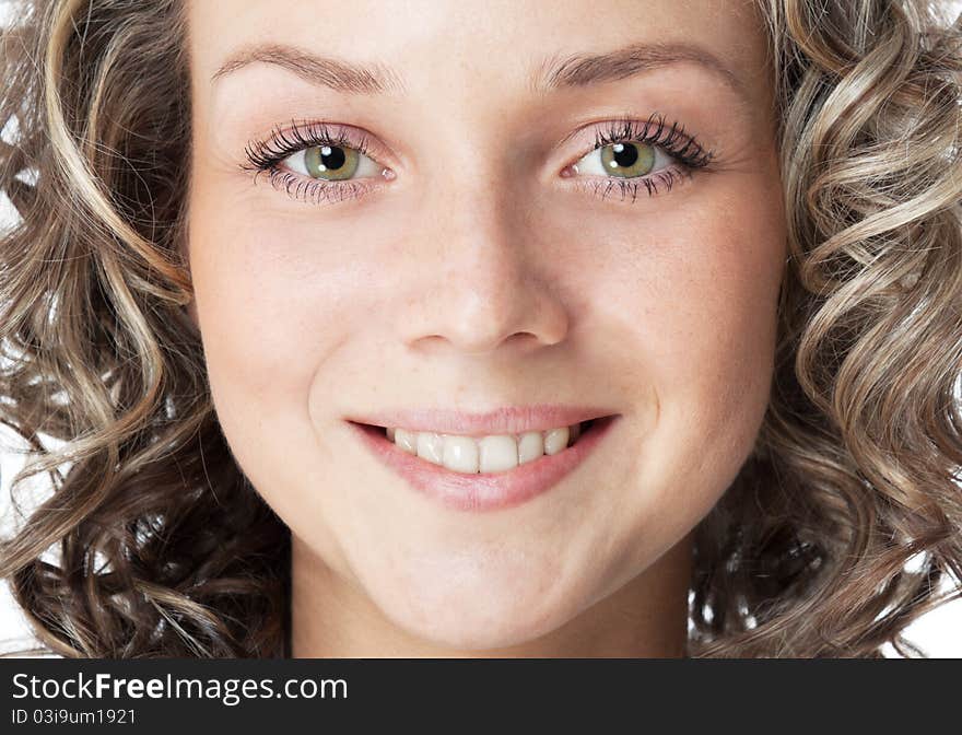 Closeup portrait of a smiling young woman (18s). Green eyes, toothy smile and curly hair