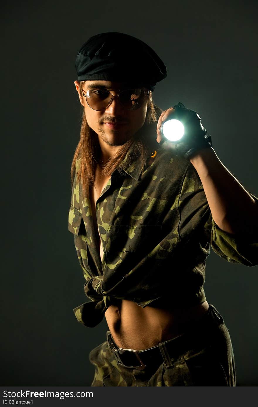 Soldier with flashligh. Studio shot over dark background.