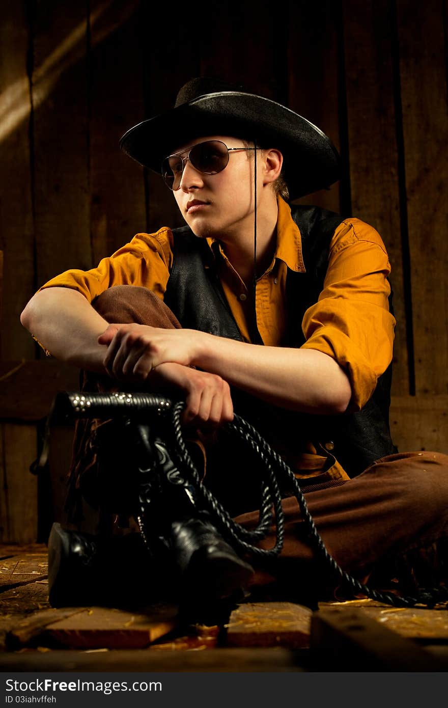 Cowboy with Black Leather Flogging Whip in his hand against wooden background