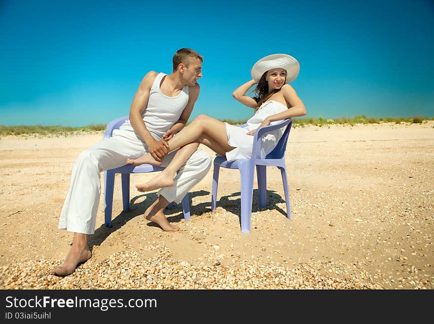 Happy romantic couple resting on beach in chairs lounge