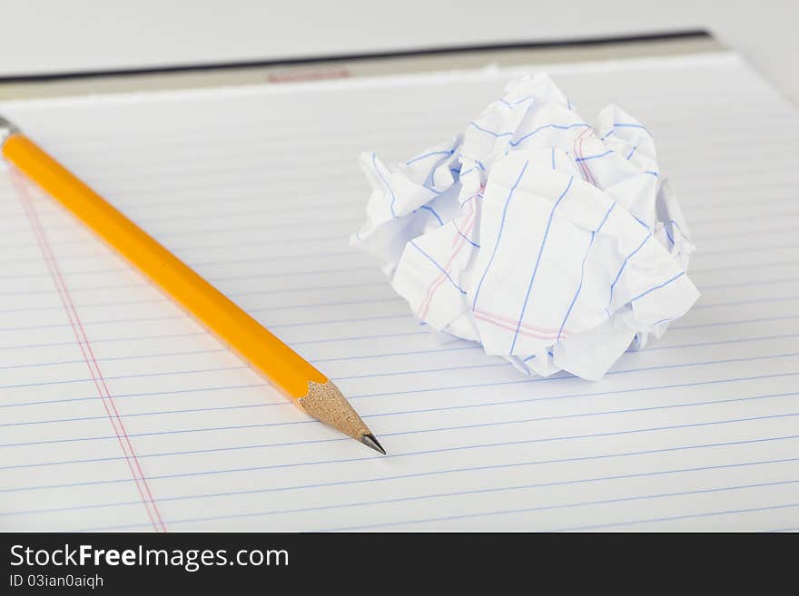 A yellow pencil on a white piece of notebook paper crumpled up. A yellow pencil on a white piece of notebook paper crumpled up