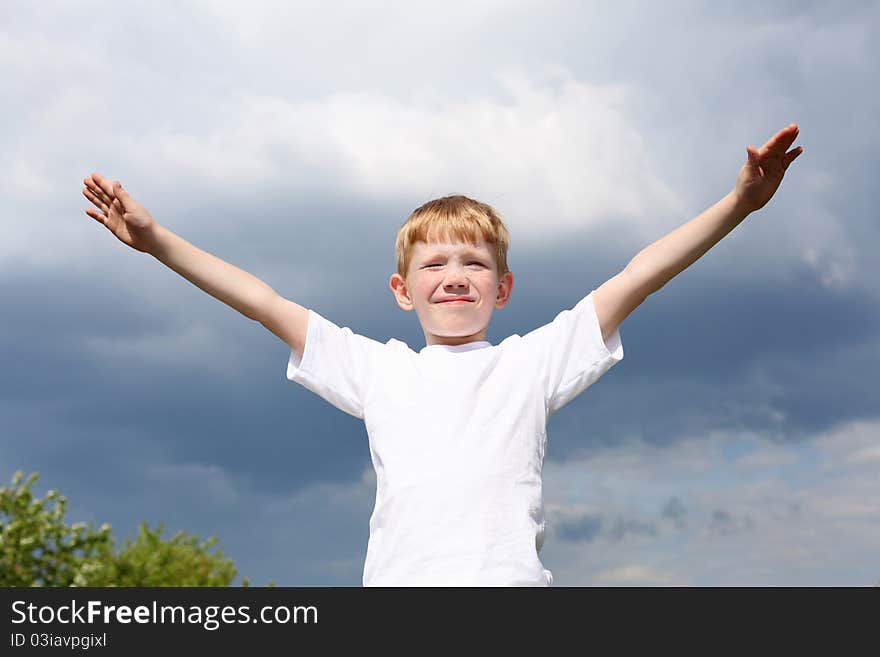 Carefree litlle boy outdoors embracing skies on lawn