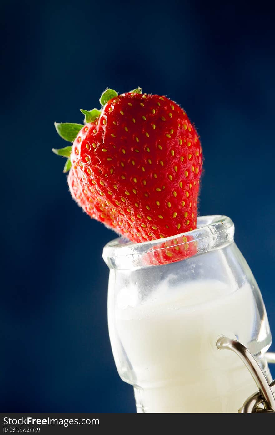 Photo of milk bottle with fresh red strawberry on it. Photo of milk bottle with fresh red strawberry on it