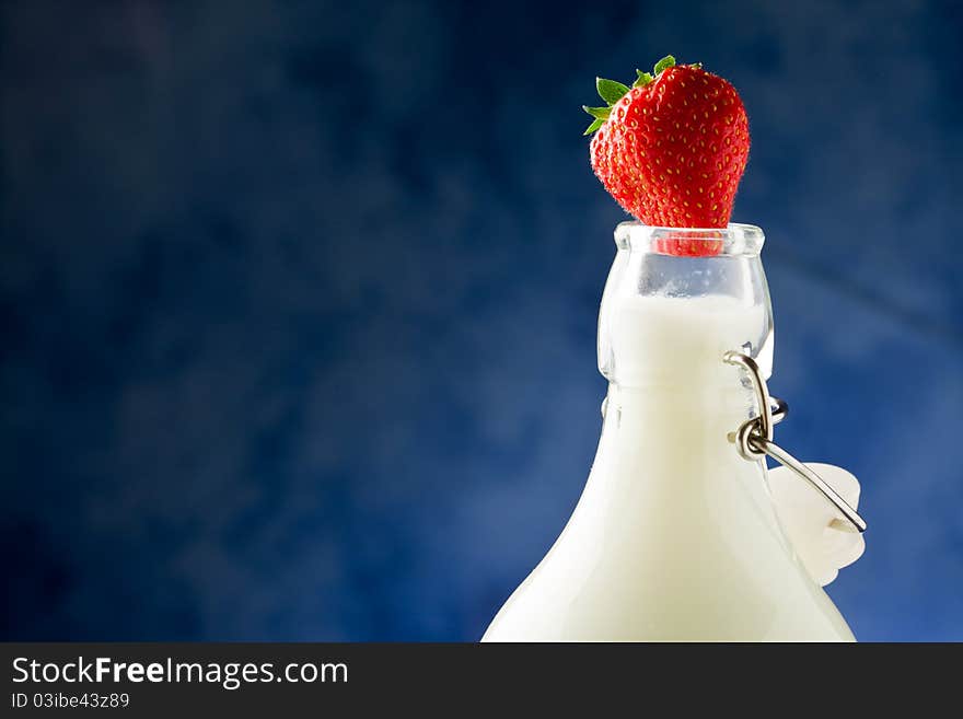 Photo of milk bottle with fresh red strawberry on it. Photo of milk bottle with fresh red strawberry on it