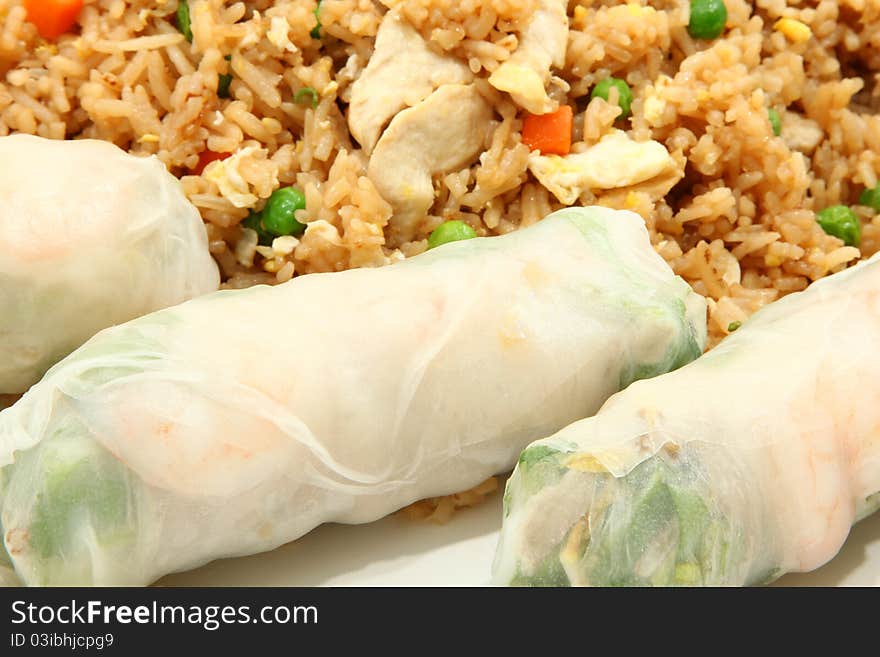 Three shrimp spring rolls on plate with chicken fried rice in background. Three shrimp spring rolls on plate with chicken fried rice in background.