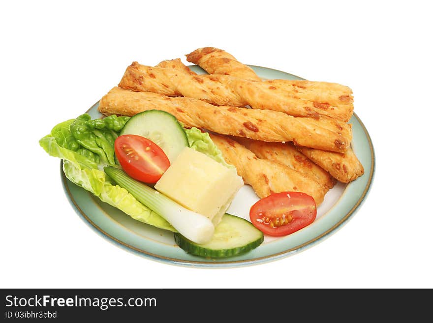 Cheese twists and salad garnish on a plate isolated against white