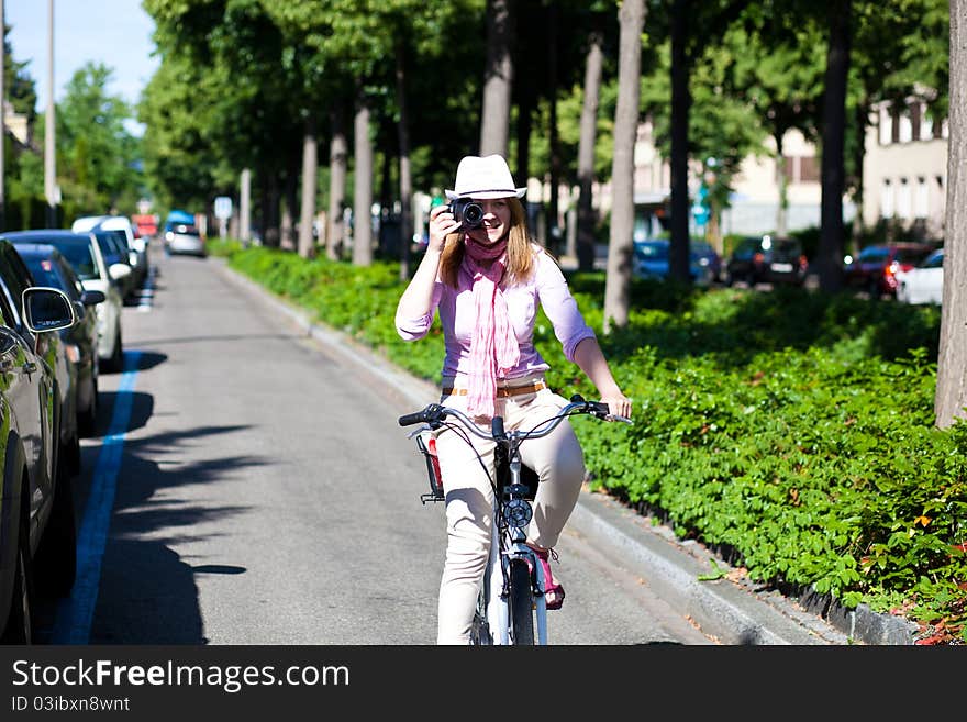 Blond cheerful woman riding a bike while making pictures