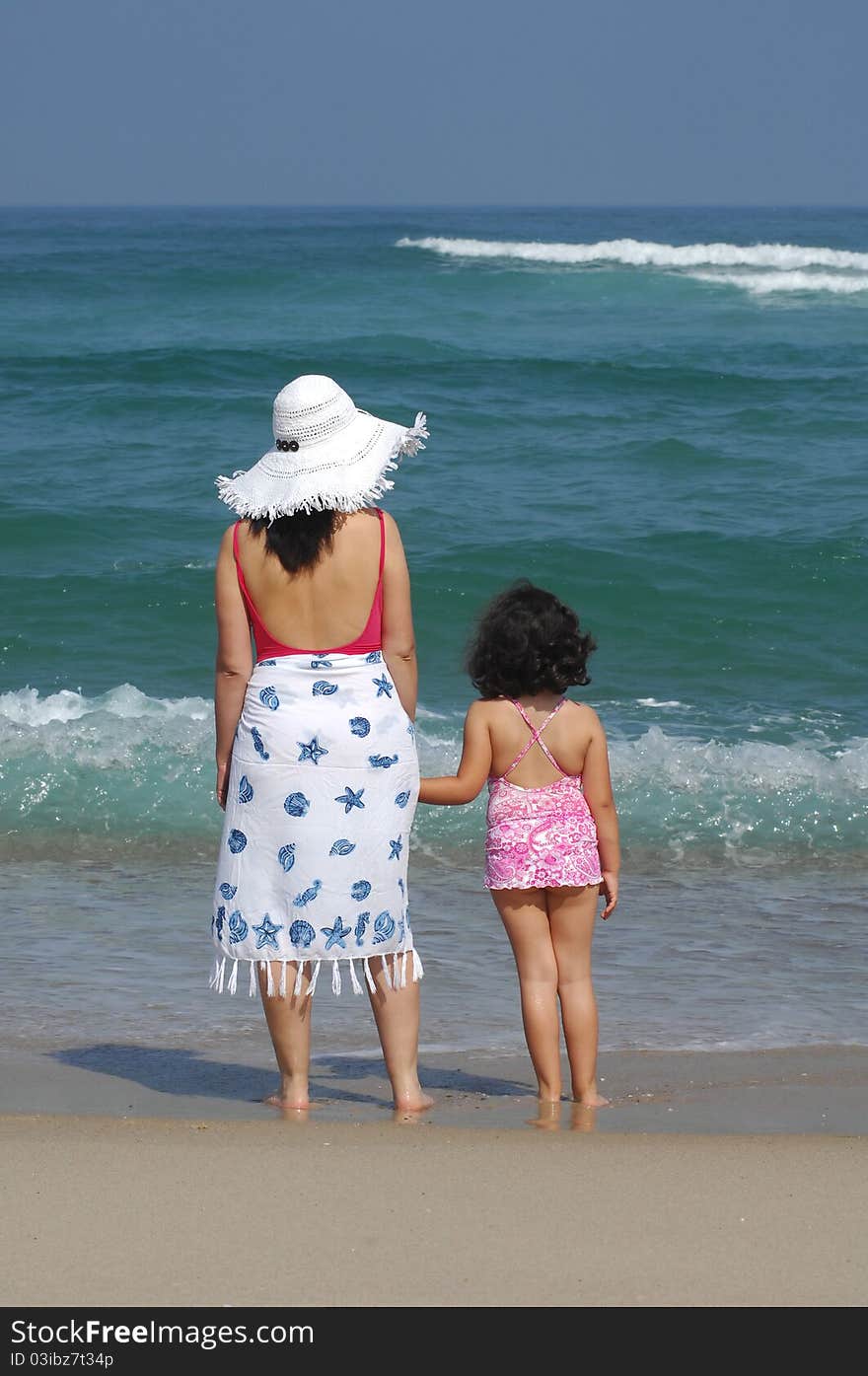 Mother and her baby in the beach near the water on the beach. Mother and her baby in the beach near the water on the beach