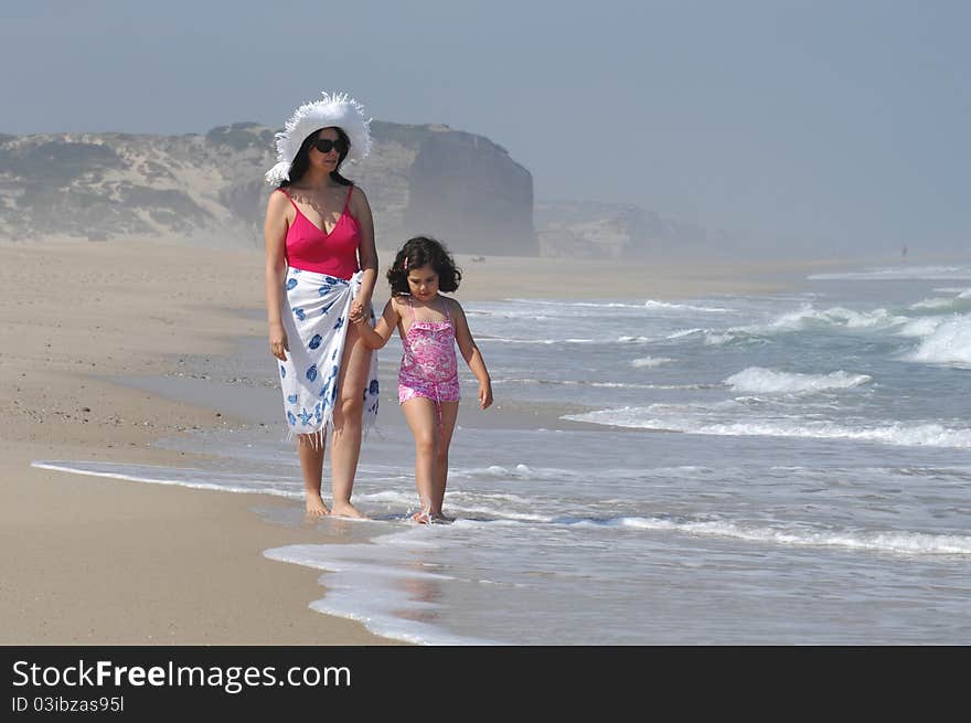 Mother and her baby in the beach near the water on the beach. Mother and her baby in the beach near the water on the beach