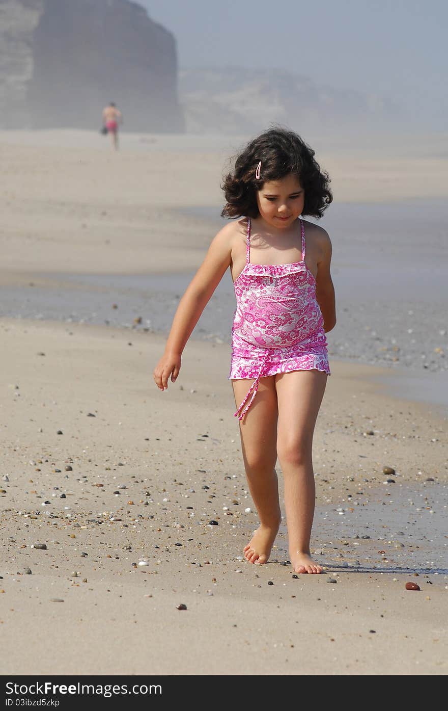 Little girl on the beach running in the coastline