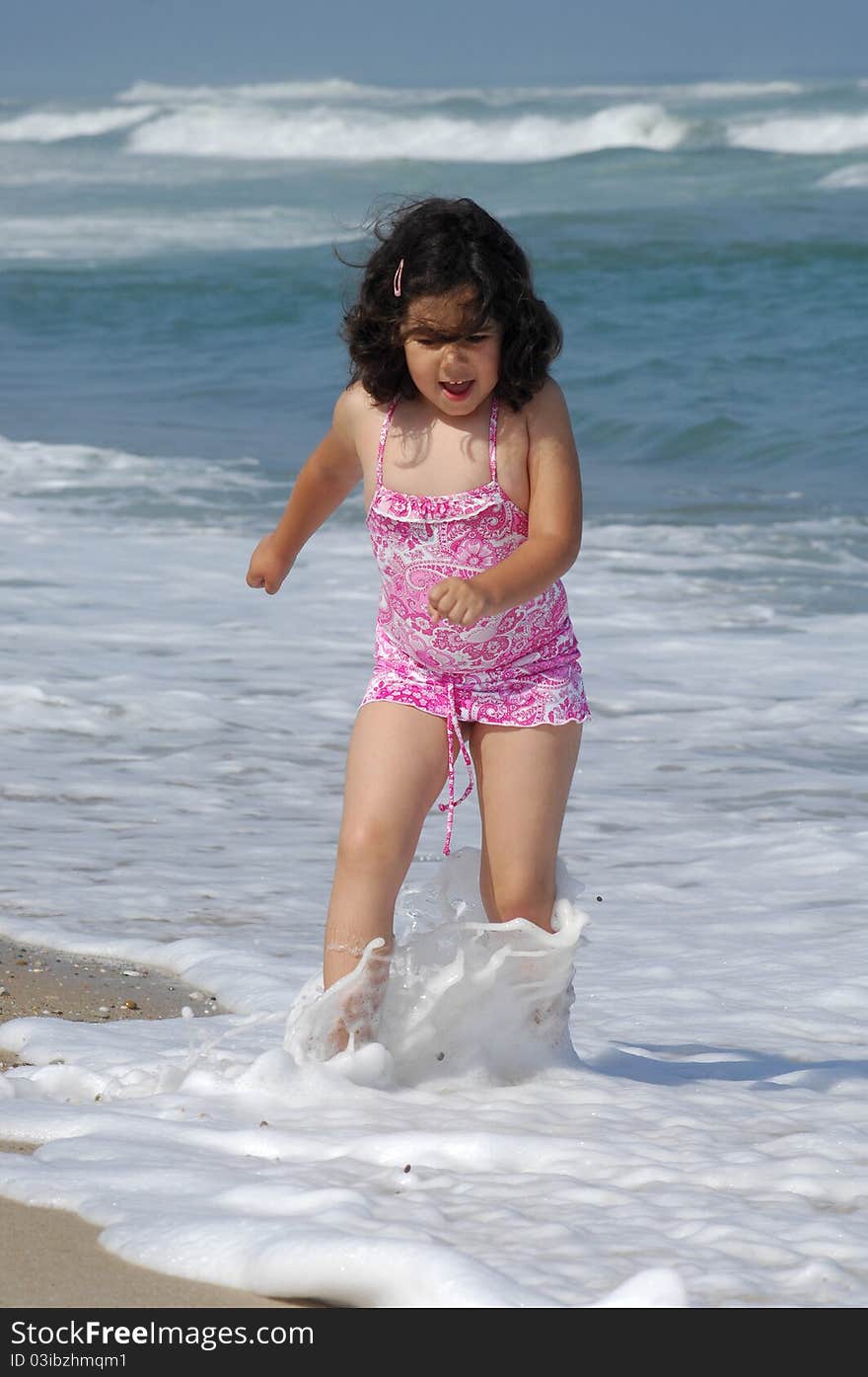 Little girl on the beach running in the coastline