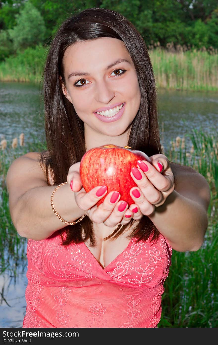 Young woman holding an apple in the park, smiling. Young woman holding an apple in the park, smiling