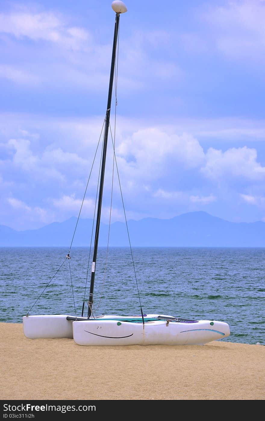 A small catamaran boat on beach sand, shown as enjoy holidy and beautiful sea view. A small catamaran boat on beach sand, shown as enjoy holidy and beautiful sea view.