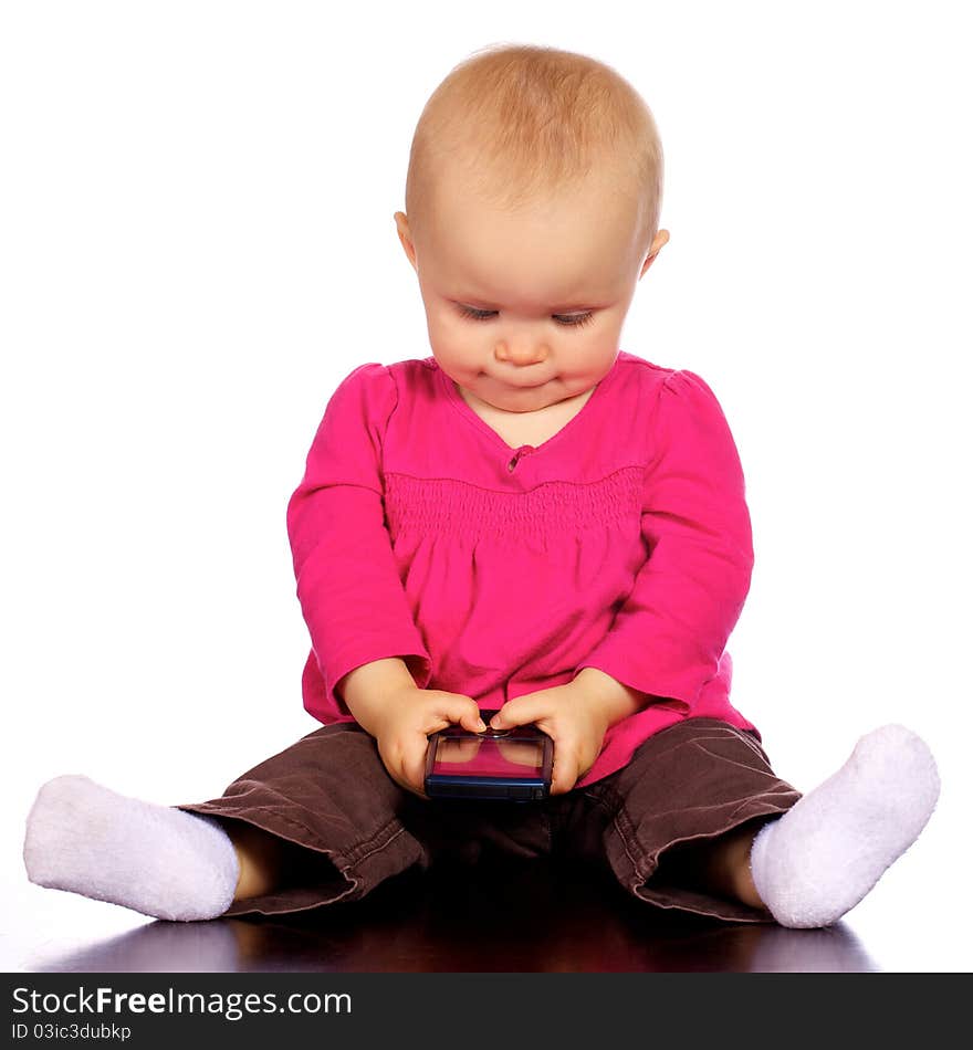 Infant baby girl sitting up looking at a cell phone, trying to figure out how it works. Infant baby girl sitting up looking at a cell phone, trying to figure out how it works