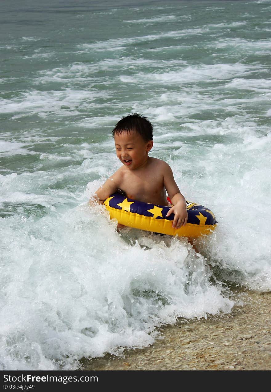 An Asian boy is playing in wave,he is at magical moments. An Asian boy is playing in wave,he is at magical moments