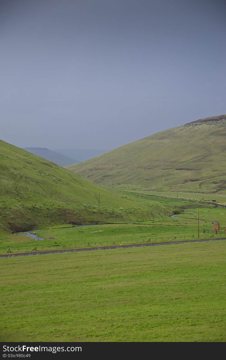 Green hills below storm clouds