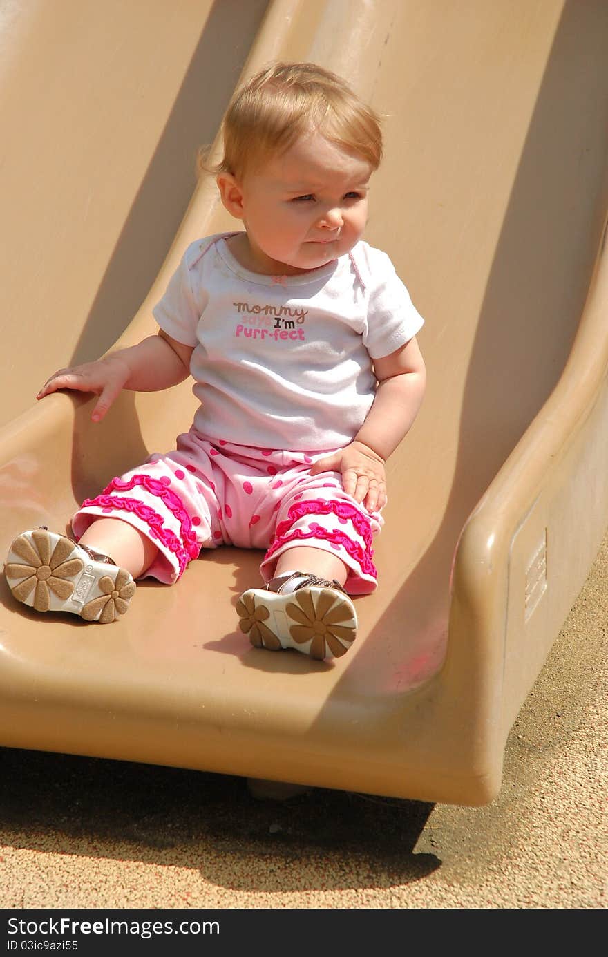 A toddler is playing on a slide and enjoying life on a warm sunny day at the park. A toddler is playing on a slide and enjoying life on a warm sunny day at the park.