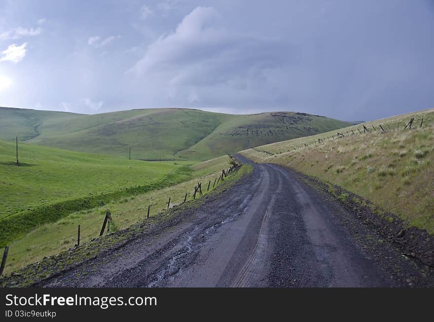 Gravel rural road beneath stormy sky