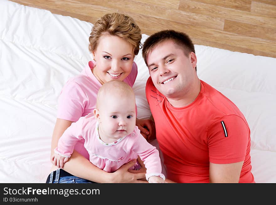 Lifestyle portrait of the Beautiful young happy family lying in bed at home - high angle