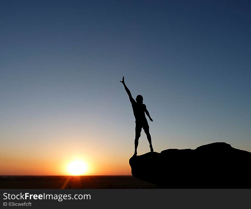 Silhouette of a man at the top of the mountain against the sky