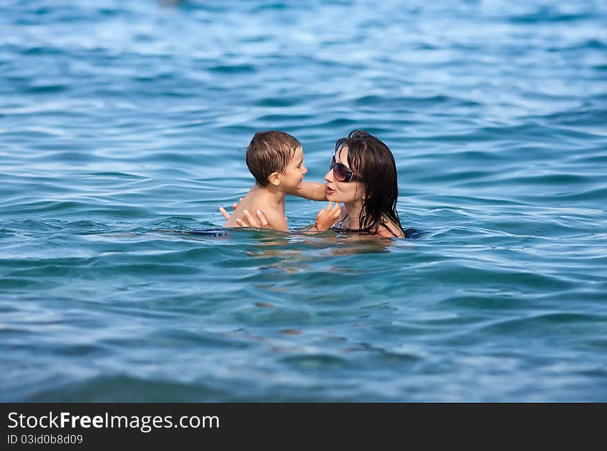 Mother and son swimming in sea