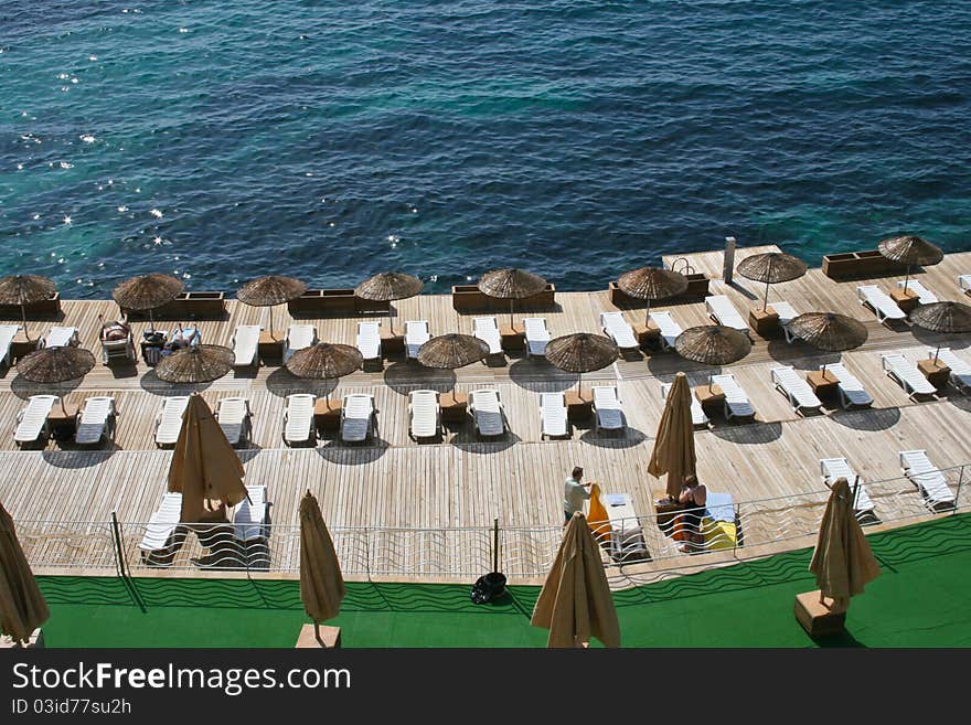 Platform with umbrellas and seats on the aegean sea shore.