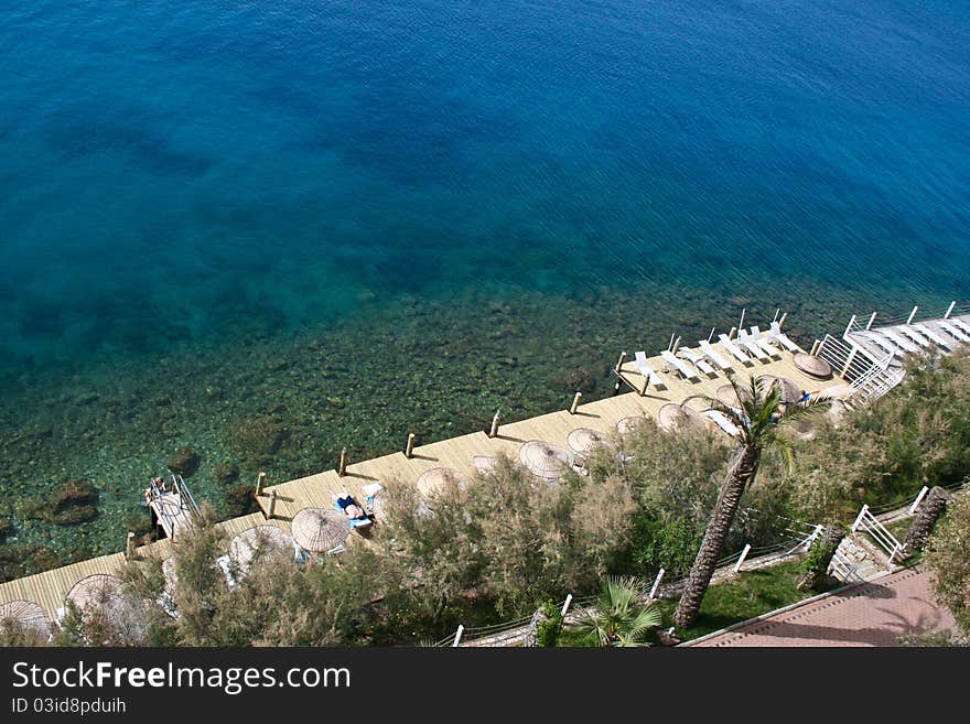 Platform with umbrellas and seats on the aegean sea shore.