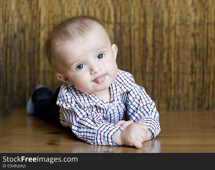 The small cheerful kid lie on a floor.