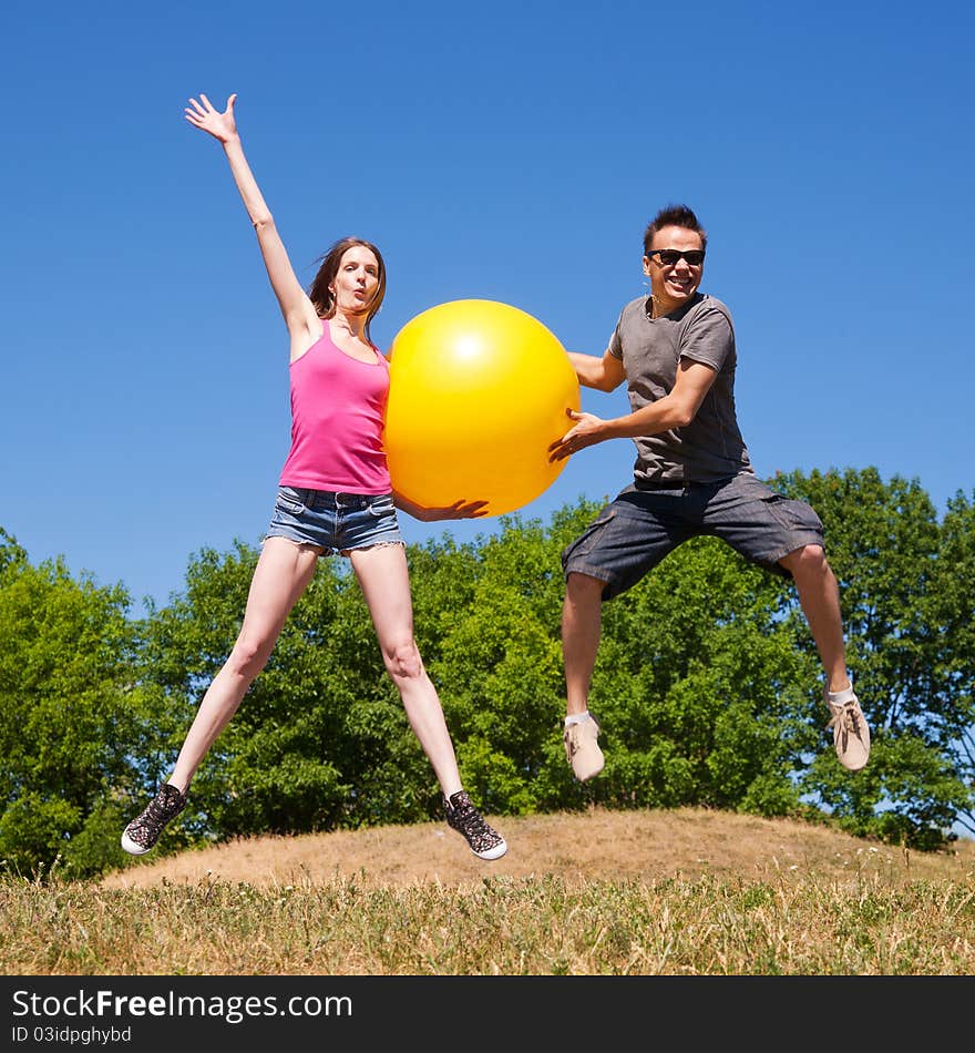 Two young people play with big yellow ball in park. Two young people play with big yellow ball in park