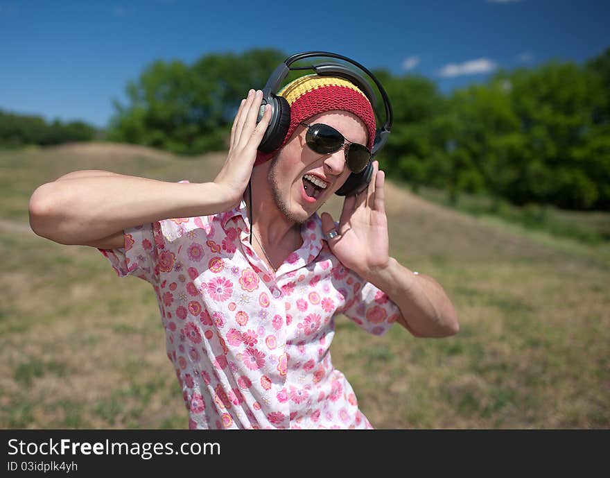 Young man in glasses with headphones in park. Young man in glasses with headphones in park