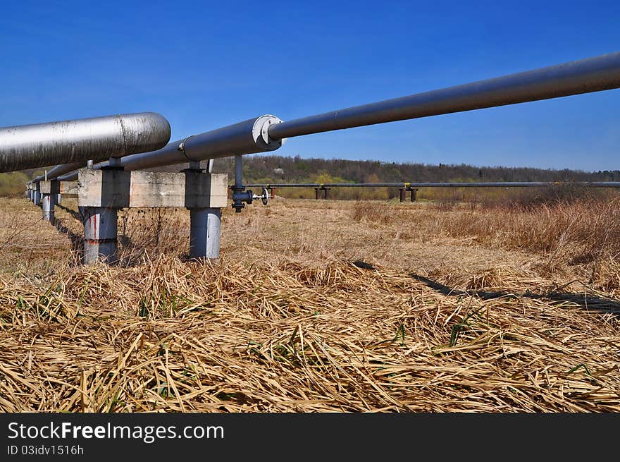 The high pressure pipeline in a summer landscape with the dark blue sky. The high pressure pipeline in a summer landscape with the dark blue sky