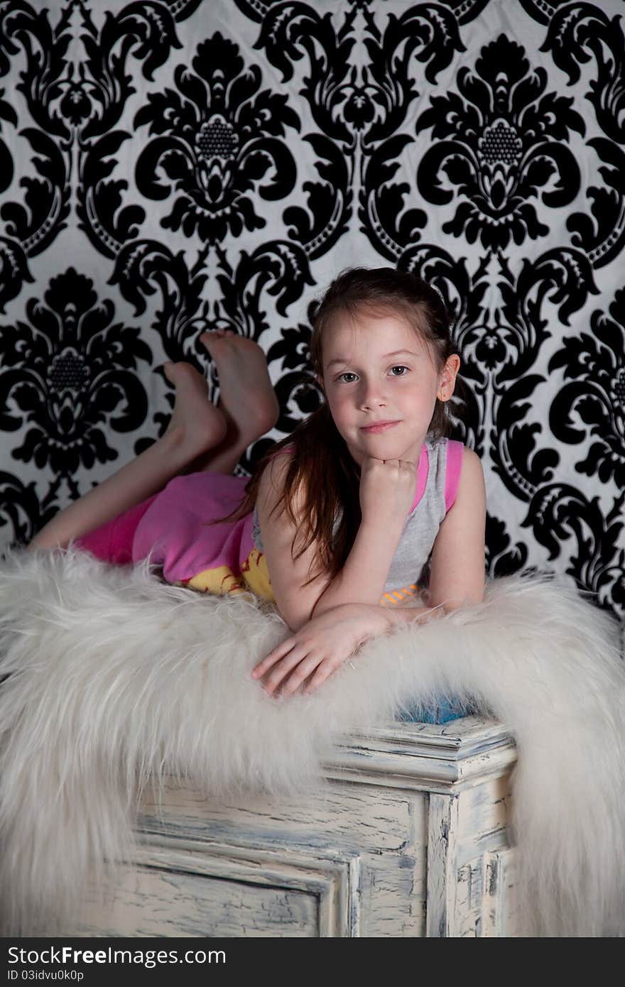 Portrait of cute girl laying on the old fashion box over the black & white background