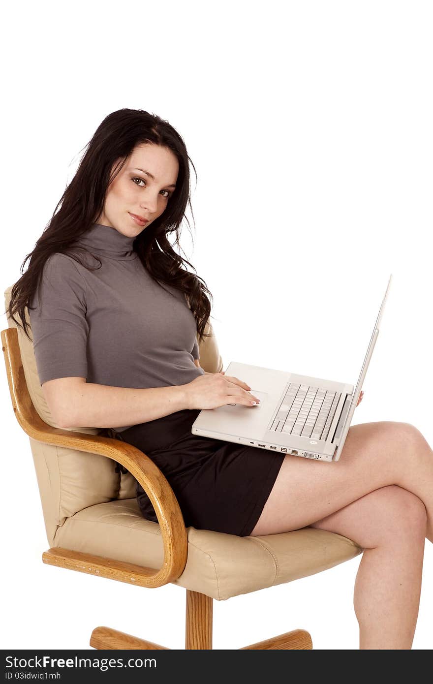 A woman sitting in her chair working on her laptop with a happy expression on her face. A woman sitting in her chair working on her laptop with a happy expression on her face.