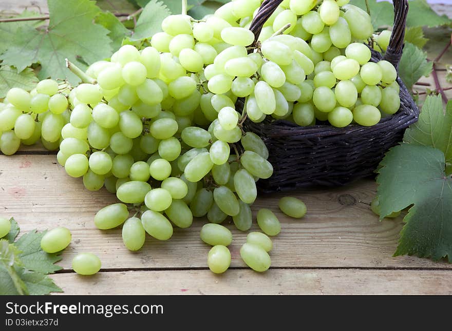 White grapes in wicker basket on a rustic wooden table