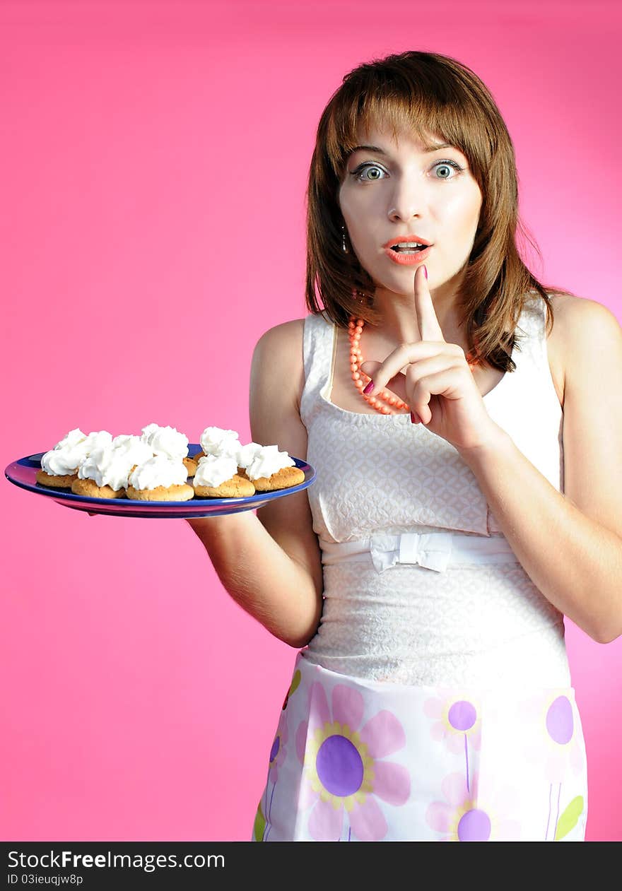 Young woman with cookies on pink background