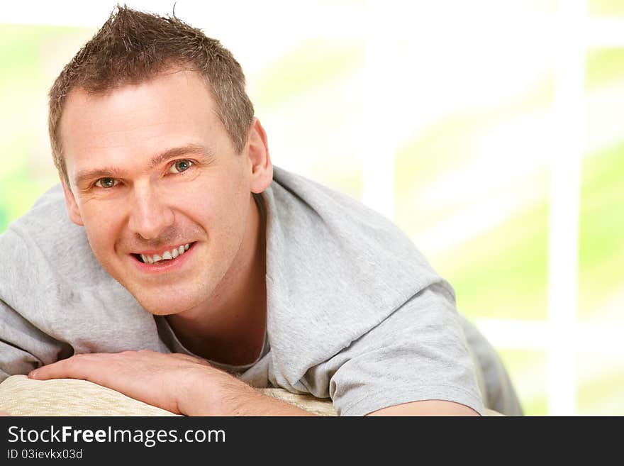 Portrait of a cheerful man relaxing on sofa at home. Indoors, horizontal color image