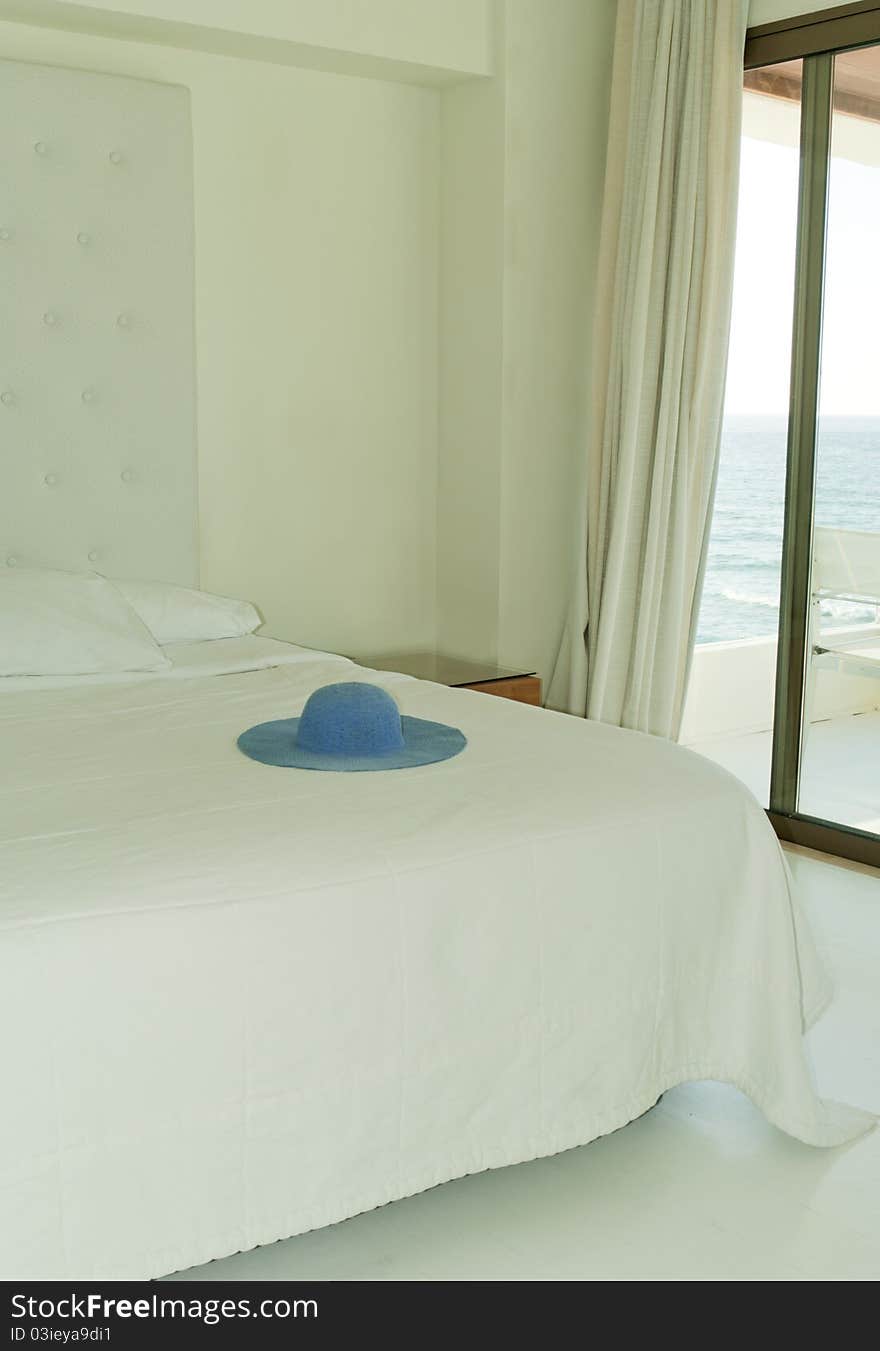 Modern room in white color with blue hat on the bed. Modern room in white color with blue hat on the bed