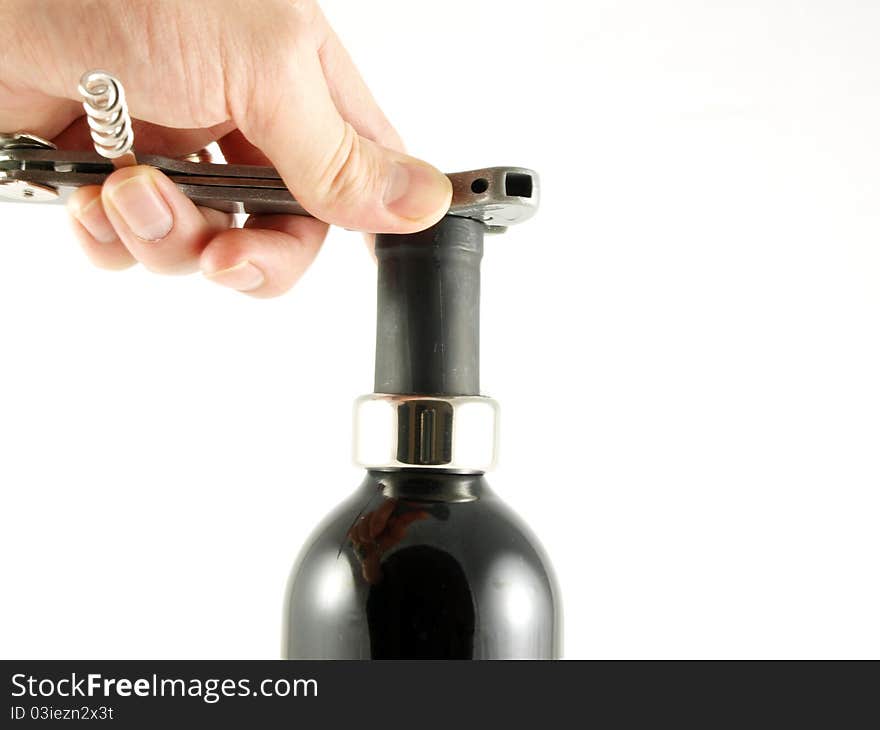 Someone opening a wine bottle, cutting off the top cover, towards white