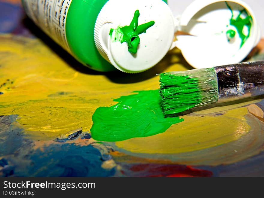 Colorful acrylic paint and paintbrush. Green and yellow paint on wooden pallette. Bottle of acrylic paint with brush. Colorful acrylic paint and paintbrush. Green and yellow paint on wooden pallette. Bottle of acrylic paint with brush.