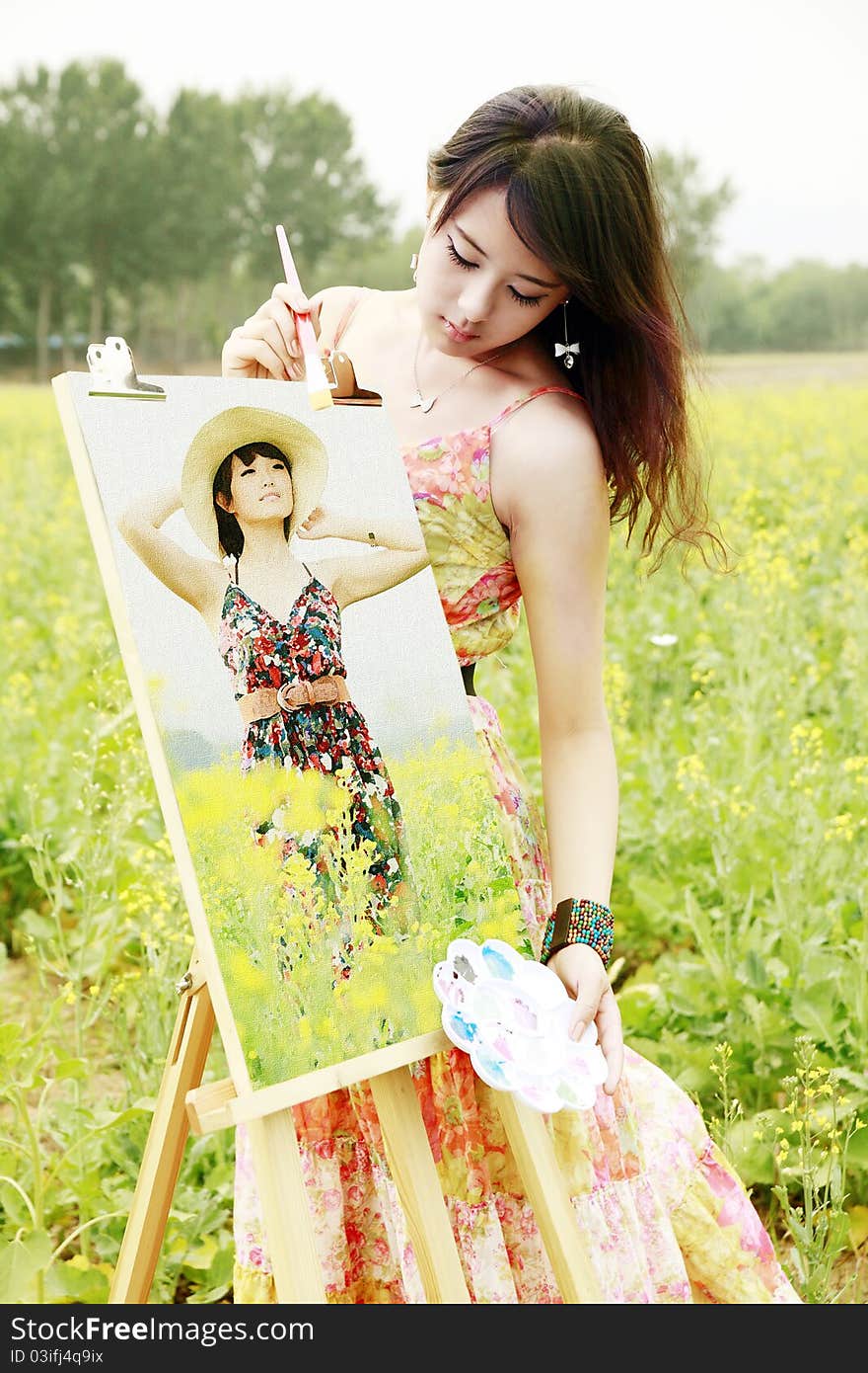 Young female artist with her oil painting in field.