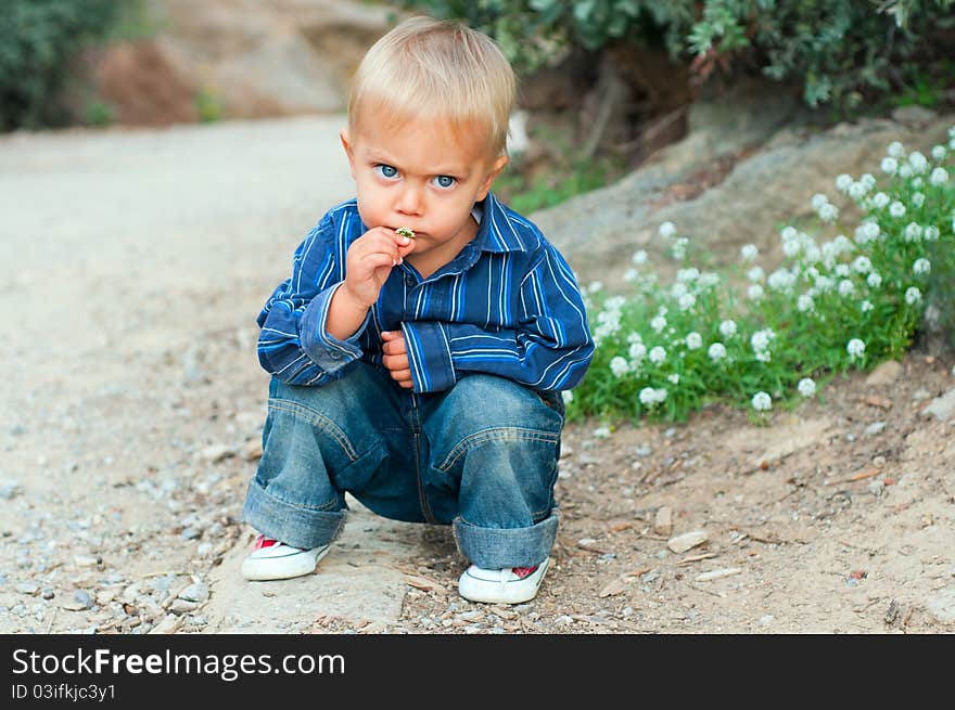 Cute 2 years old boy sitting on the footpath in the park. Cute 2 years old boy sitting on the footpath in the park