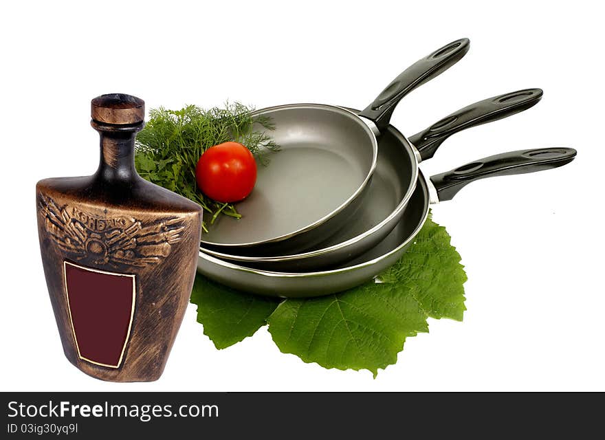 Three frying pens,greens,tomato and ceramic vessel. Three frying pens,greens,tomato and ceramic vessel.