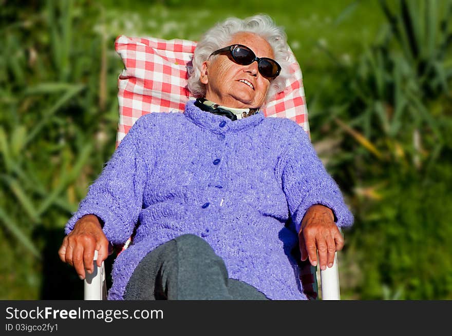 Senior woman has a rest in a chair-bed.