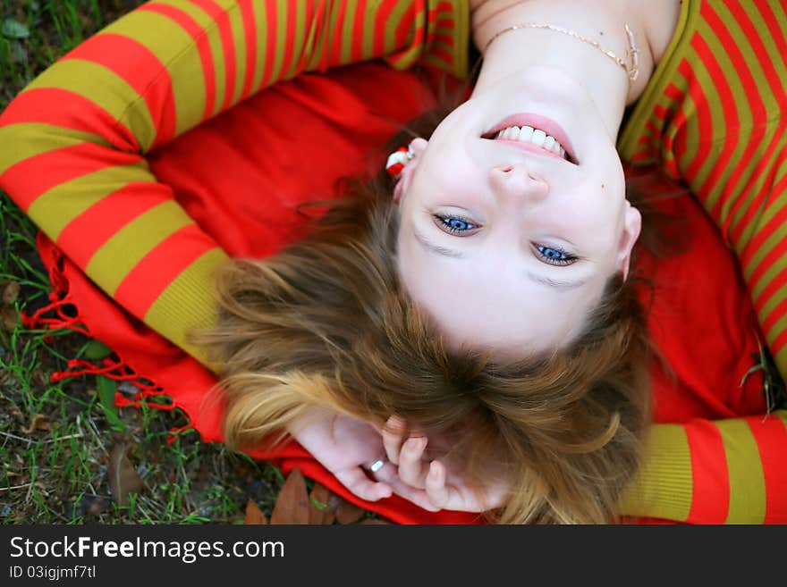 Portrait of a girl in a bright colored striped sweater lying on the grass. Portrait of a girl in a bright colored striped sweater lying on the grass